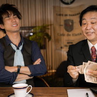 貸そう通貨で現金を数える男性と交渉する会社員の写真