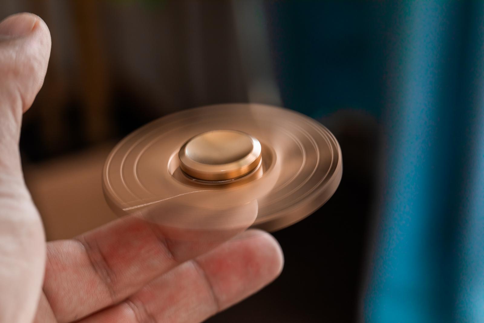 手のひらで回すメタリックゴールドのハンドスピナーが回転している様子