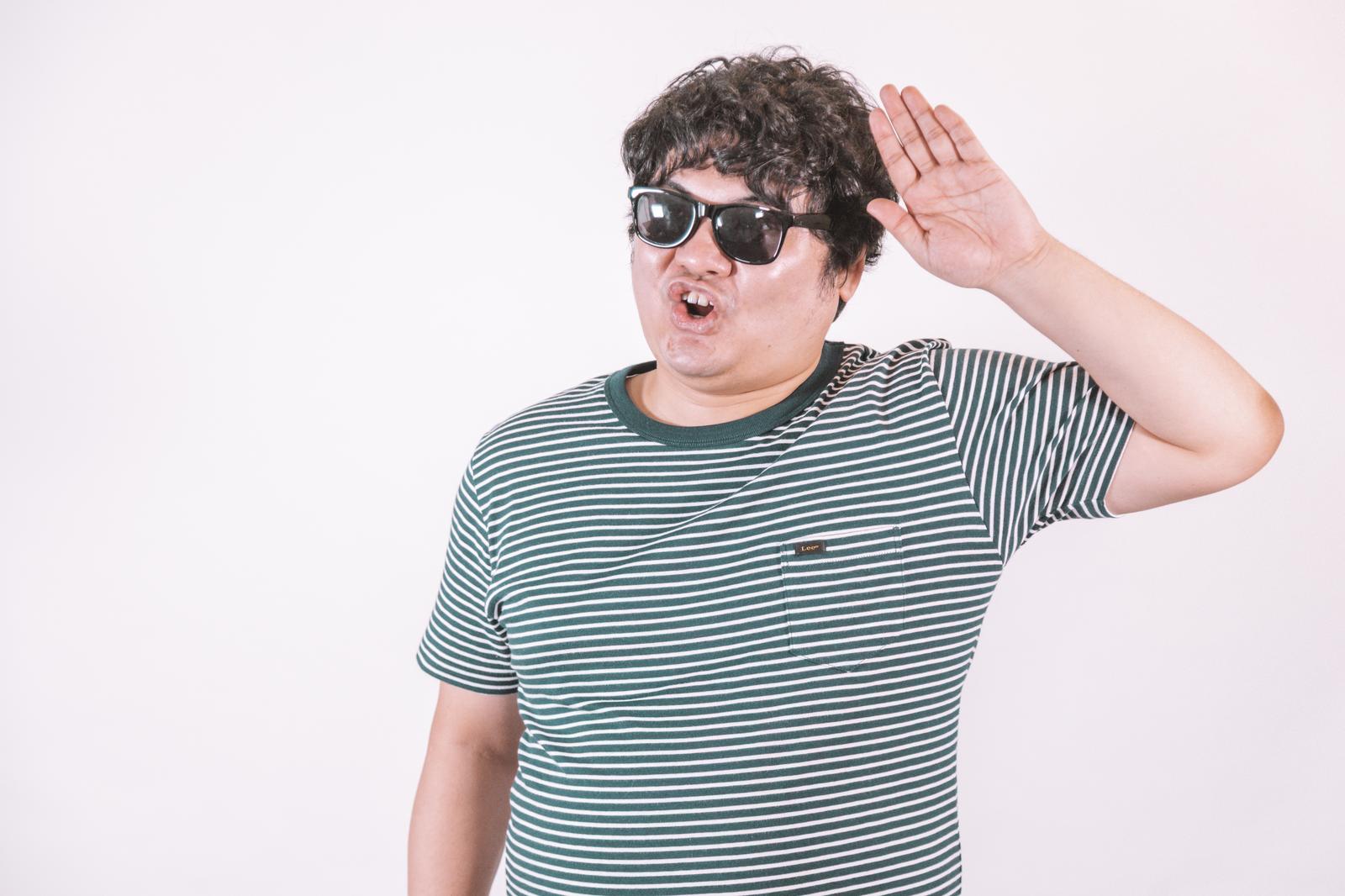 サングラスをかけた男性が両手を上げてアクティブなリアクションをしている［モデル：段田隼人］