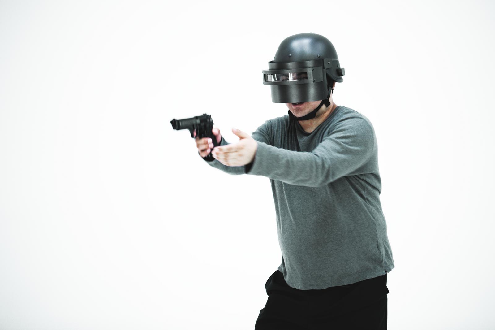 ヘルメット姿でハンドガンを構える男性［モデル：段田隼人］