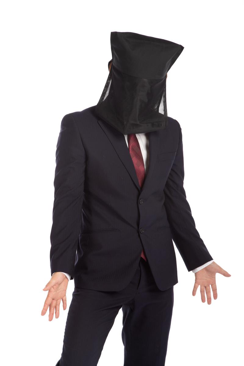 黒い布で頭を隠してスーツ姿でプレゼンする人物［モデル：鈴木秀］