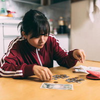 ATMの中の人になって小銭を数える女性の写真