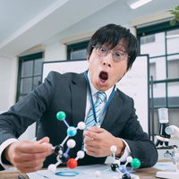 実験室で分子構造モデルを手に驚く男性研究者の写真