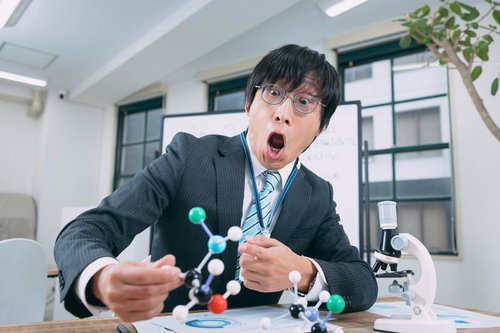 実験室で分子構造モデルを手に驚く男性研究者
