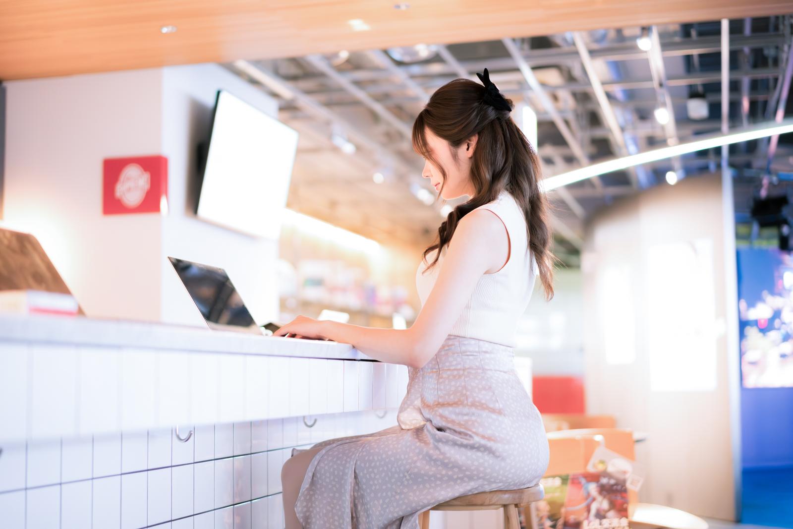 商業施設のカウンターでノートPCを操作する女性［モデル：れいか氏］
