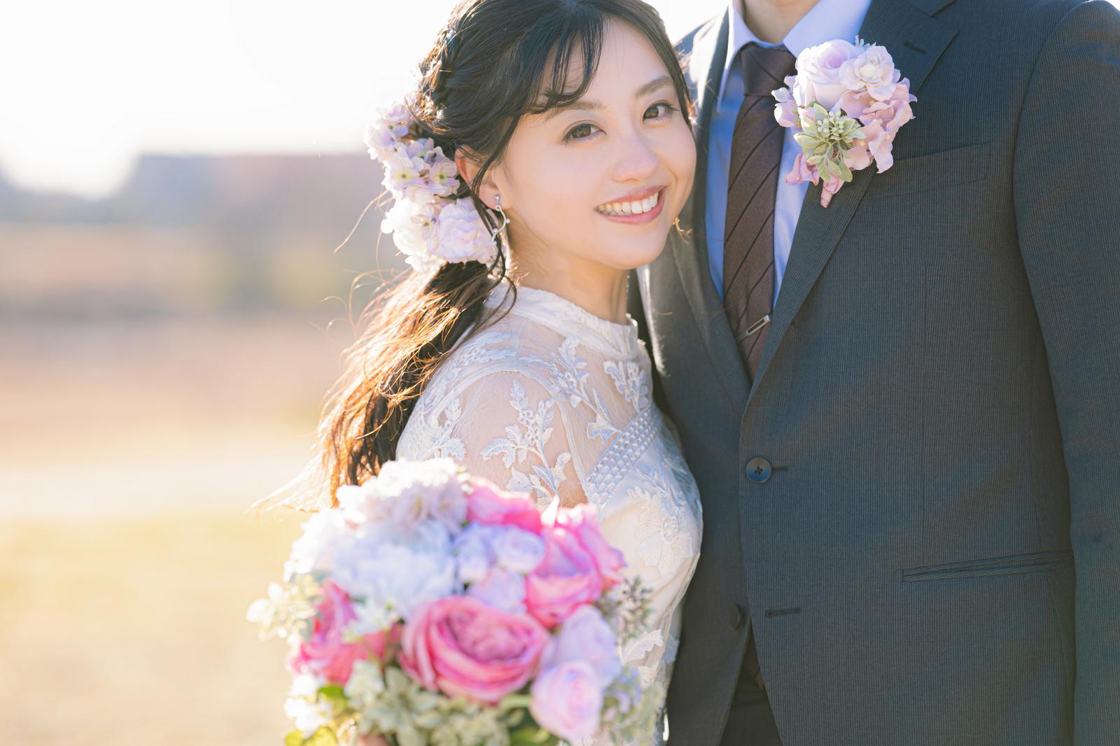 屋外で笑顔を見せる花嫁と花婿［モデル：河村友歌］