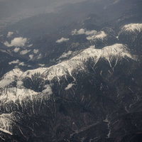 山頂付近に雪が残るアルプスの山脈を上空から撮影の写真