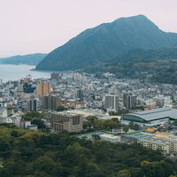 山に囲まれた別府温泉街の景観とグローバルタワーの写真