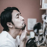 あごに吹き出物ができた無精髭の男性が鏡で肌を確認の写真