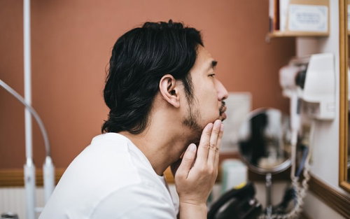 髭面の男性が洗面所で行う今日はお肌の調子がイマイチな朝のスキンケア