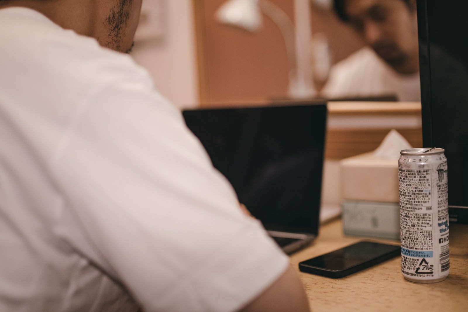 デスクでうなだれながらエナジードリンクを飲む疲れた男性［モデル：大川竜弥］
