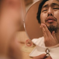 右の親知らずが痛む無精髭男子が鏡を見てしかめっ面の写真