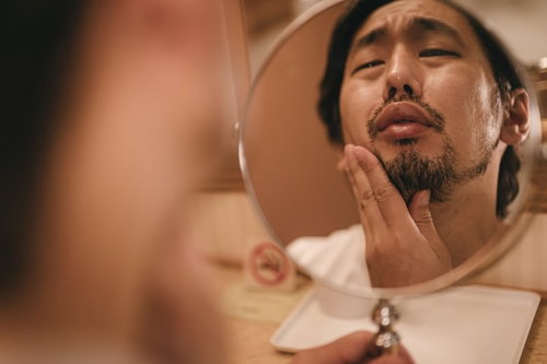 右の親知らずが痛む無精髭男子が鏡を見てしかめっ面