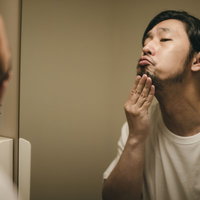 洗面台の鏡で髭を整える無精髭の男性のグルーミングの写真