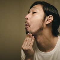 髭の伸び具合を確認する無精髭の男性のグルーミングの写真