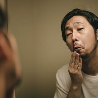 デスマ中は髭が伸びるの早いなぁ、洗面台で無精髭を確認する男性の写真