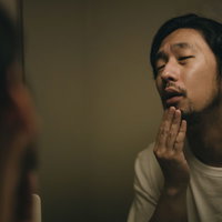 鏡に映る無精髭のしかめっ面の髭男子の朝の身だしなみチェックの写真