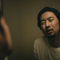 寝起きで目が開かない無精髭の男性の写真