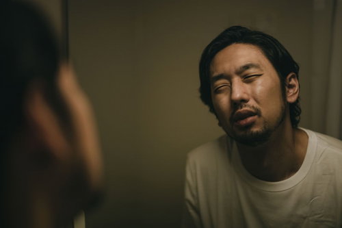 寝起きで目が開かない無精髭の男性