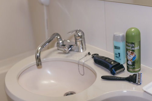 白い洗面台に置かれた髭剃りとシェービングクリームのセット
