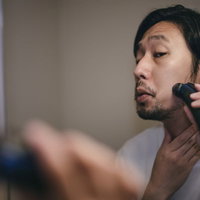もみあげから髭にかけてシェーバーでシェービングする男性の写真