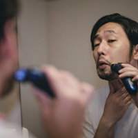 長く伸びた髭がシェーバーに絡む男性の髭剃りの写真