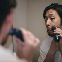 洗面台の鏡を見ながらシェービングする男性の写真
