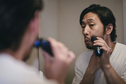 洗面台の鏡を見ながらシェービングする男性