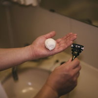 手のひらに泡立つシェービングクリームとシェーバーの写真