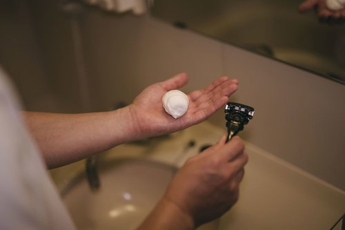 手のひらに泡立つシェービングクリームとシェーバー