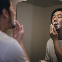 洗面所でシェービングクリームを髭に付ける男性の写真
