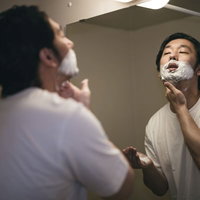 剃刀負けしないように念入りにシェービングクリームで泡タイムを過ごす男性の写真
