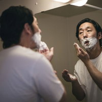 髭剃り前にシェービングクリームを泡立てて塗る男性の写真