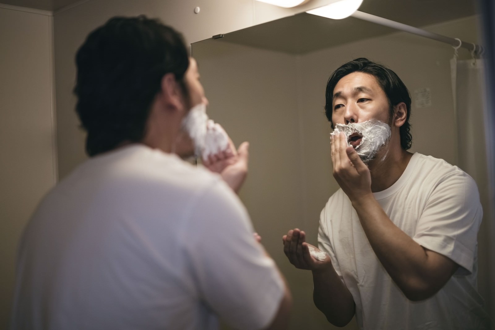鼻下に白いシェービング剤の泡を塗り込む男性［モデル：大川竜弥］