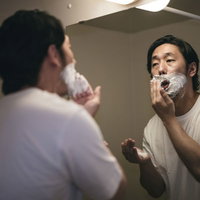 鼻下に白いシェービング剤を塗り込む男性の朝の髭剃り準備の写真