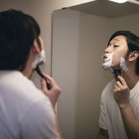 シェービング剤の泡で髭を剃り上げる男性の朝の身だしなみの写真