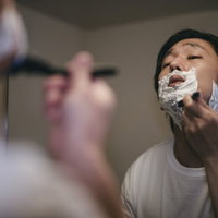 顎の下を入念に剃り上げるシェービング中の男性の写真