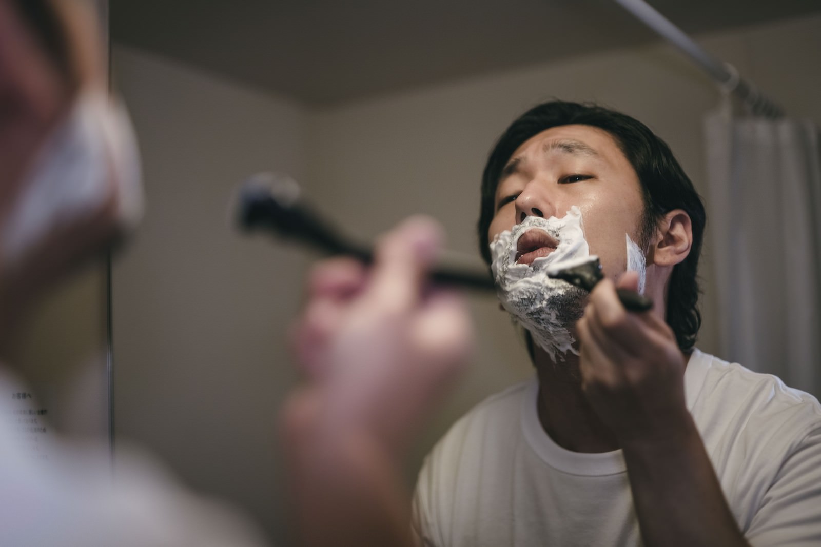 白いシェービングクリームを顔に塗る男性の手元［モデル：大川竜弥］