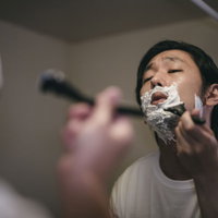 シェービング用の泡で髭剃りする髭男性のモーニングルーティーンの写真