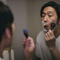 泡がない部分を丁寧に深剃りする男性の髭剃りの写真