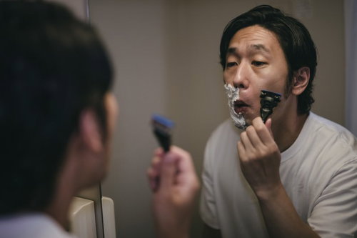泡がない部分を丁寧に深剃りする男性の髭剃り
