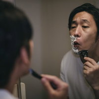 顎のラインを丁寧に深剃りするカミソリでのシェービング男性の写真