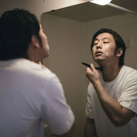 シェービングの最後の仕上げをする髭男性、洗面所で丁寧に髭剃りの写真