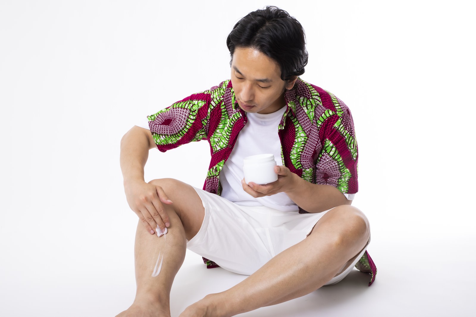ムダ毛処理後にボディクリームで脚をケアする白いタンクトップの男性［モデル：大川竜弥］