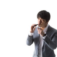 加熱式たばこを吸いながら指差し確認をするグレーのスーツ姿の男性の写真