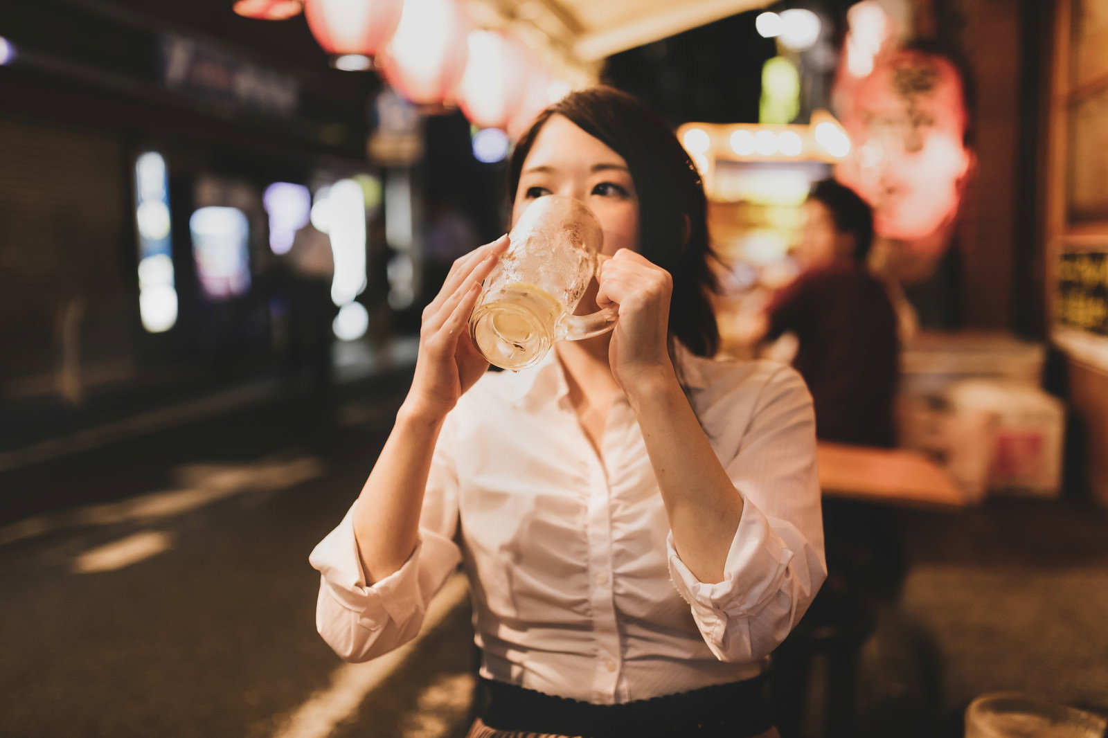 居酒屋の店内でチューハイを手に持って飲んでいる女性［モデル：シマヅ］