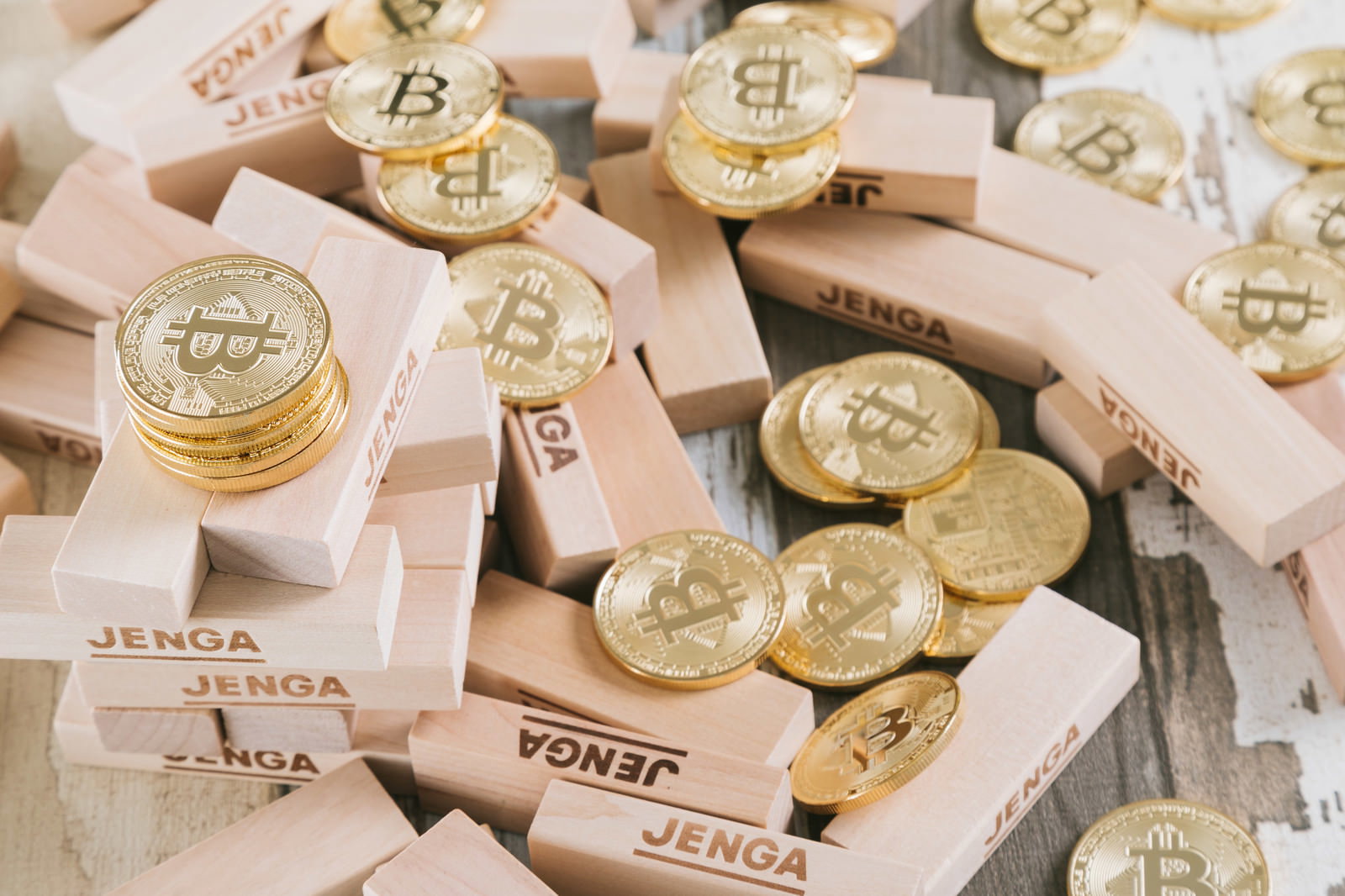 ビットコインシンボル入り木製ブロックが傾き、金色のコインが落下している