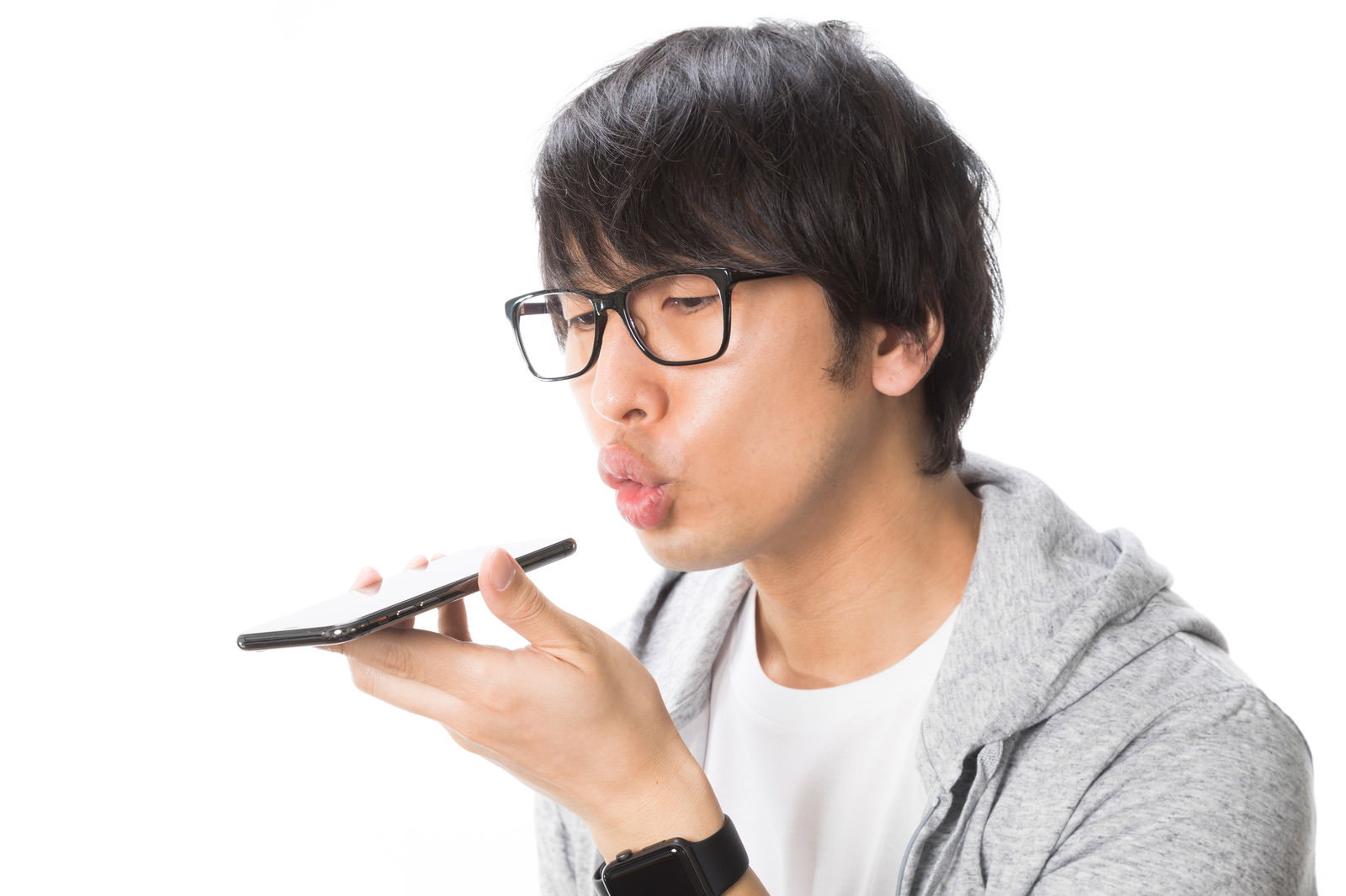 グレーのパーカーを着た眼鏡の男性がスマートフォンに向かって話している［モデル：大川竜弥］