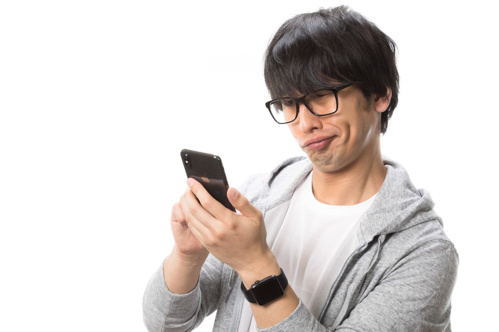 グレーのパーカーを着た眼鏡の男性がスマートフォンを見て困った表情をしている［モデル：大川竜弥］