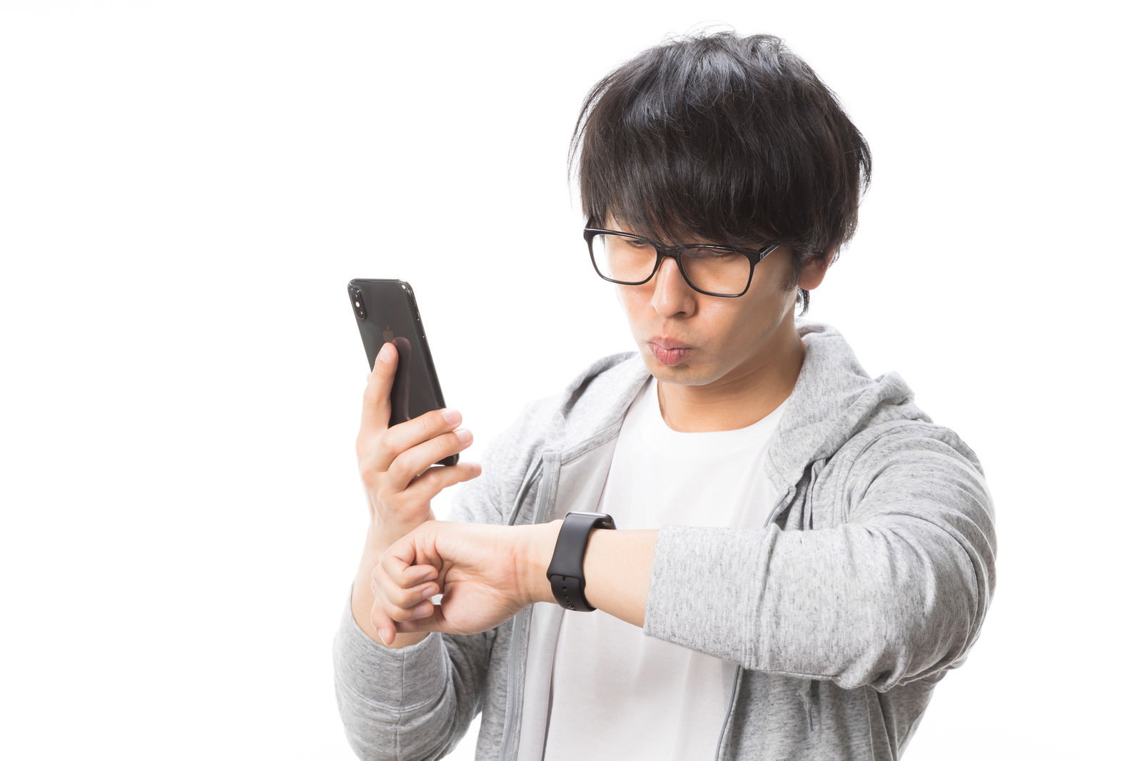 スマホを持ちApple Watchを確認する眼鏡の男性［モデル：大川竜弥］